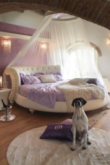 Round white leather four-poster bed in the bedroom