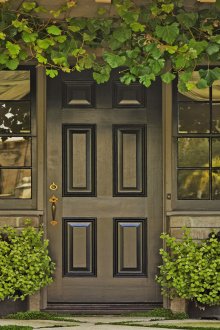 Черна входна врата между прозорците