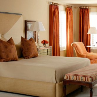 Оранжеви завеси, фотьойл и диван в спалнята