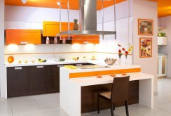 Orange, white and brown colors in the interior of the kitchen with a peninsula