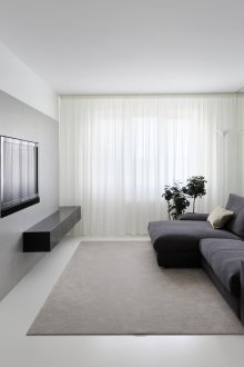 Schwarzes Sofa in einem weißen Wohnzimmer im Stil des Minimalismus