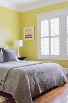 Katil kelabu dan kerusi berlengan putih dan kuning di dalam bilik tidur