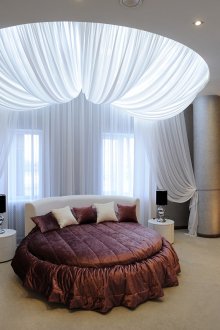 Burgundy katil pusingan putih di dalam bilik tidur dengan hiasan kain