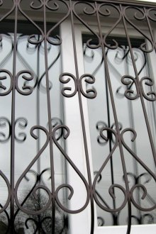 Тъмна решетка за прозорци с елементи от ковано желязо.