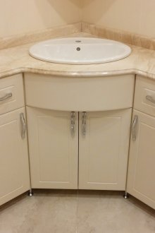 Ъглов бежов шкаф под мивката в банята