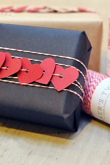 Подаръчна украса с тъмна хартия и въже със сърца.