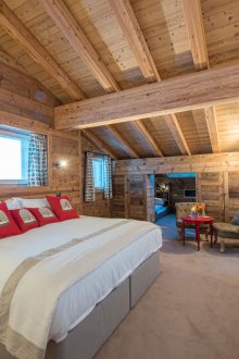 Просторна спалня с червени възглавници в селски стил под покрива