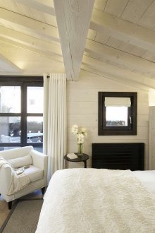 Малка таванска спалня с леки облицовки и мебели.