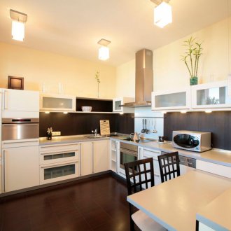 Бял опънат таван с ярко осветление в кухнята