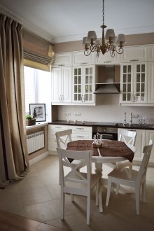 Комбинация от кремави обикновени и римски завеси в кухнята