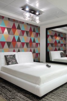 Kertas dinding terang dengan cetakan geometrik di dalam bilik tidur putih