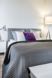 Сива спалня с лилави акценти.