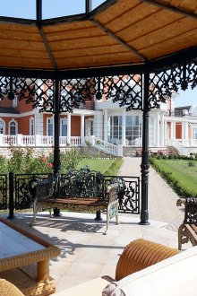 Беседка с елементи от ковано желязо и мебели от ракита.