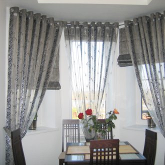 Curtains on grommets made of transparent and dense stripes of fabric in the kitchen