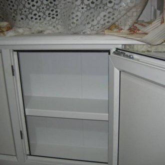 Refrigerator under the window with shelves