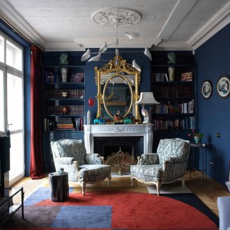 Сини стени и червени завеси и акцент върху килима в хола