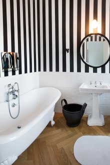 Комбинацията от обикновена бяла повърхност и черно-бели райета тапет в банята