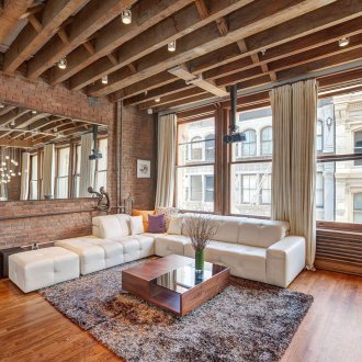 벽돌 벽이 있는 거실의 천장에 있는 나무 기둥.